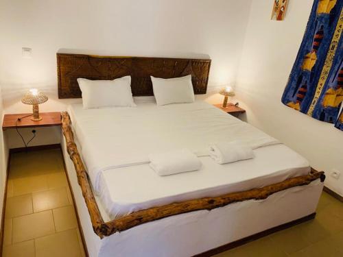 a bedroom with a bed with white sheets and two lamps at Villa Nemocotier in Cap Skirring