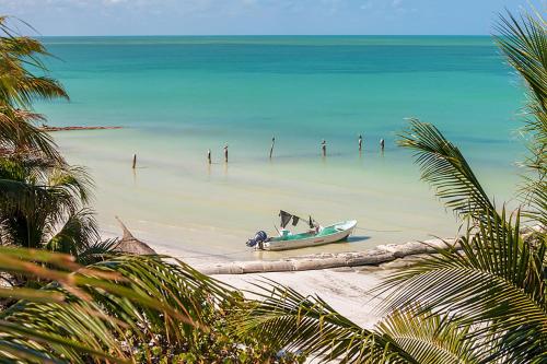 a boat on a beach with people in the water at Beachfront Hotel La Palapa - Adults Only in Holbox Island