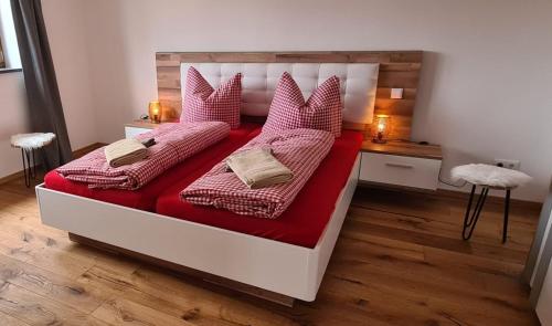 Schlafzimmer mit einem Bett mit roter Bettwäsche und Kissen in der Unterkunft Ferienwohnung mit Sauna am Alpsee in Bühl am Alpsee