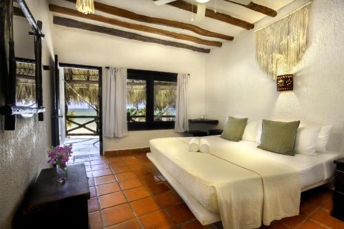 a bedroom with a bed and a large window at Beachfront Hotel La Palapa - Adults Only in Holbox Island