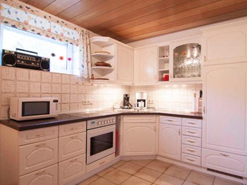 a white kitchen with white cabinets and a window at Haus Meckbach in Bad König