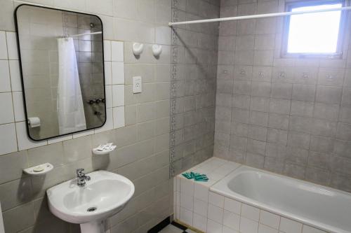 y baño con lavabo, bañera y espejo. en Temporales Ushuaia - Casa Magallanes en Ushuaia