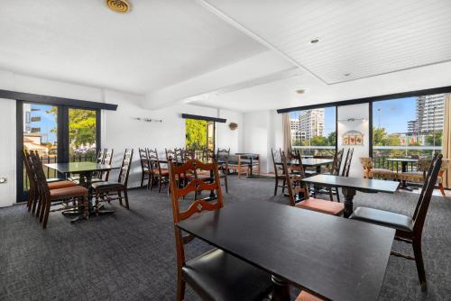 a dining room with tables and chairs and windows at Hamilton Brisbane Airport Hotel in Brisbane