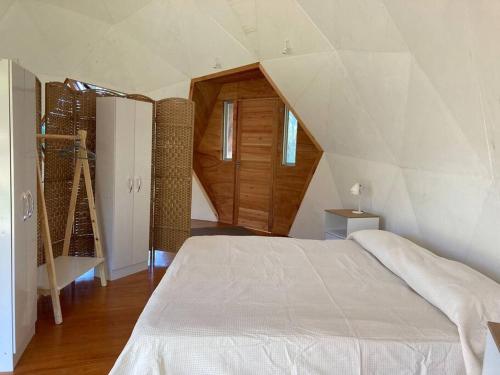 Un dormitorio con una cama blanca y una escalera en Domo en la playa, en Sauce de Portezuelo