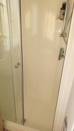 La salle de bains est pourvue d'une douche avec une porte en verre. dans l'établissement Seaview Homes, à Hastings
