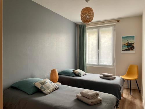 dwa łóżka w pokoju z oknem w obiekcie « BLEU COMME MER » à deux pas des plages w mieście Concarneau