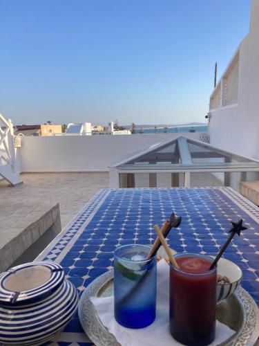 een tafel met borden en een drankje op een patio bij Beau riad en médina, lumineux et avec terrasse privée sur mer in Essaouira