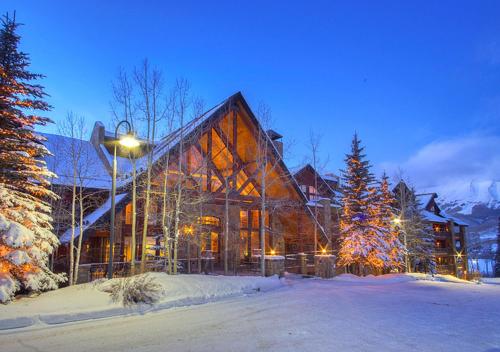 a large wooden house in the snow at night at Bear Creek Lodge by Alpine Lodging Telluride in Telluride