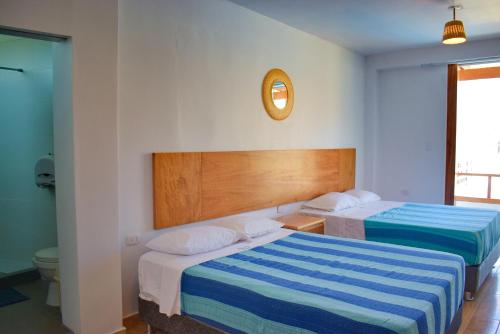 een hotelkamer met twee bedden en een klok aan de muur bij Prim Hotel Vichayito in Vichayito