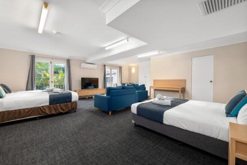 a hotel room with two beds and a blue couch at Alloggio Hamilton Brisbane Airport in Brisbane
