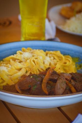 a plate of food with noodles and meat on a table at Prim Hotel Vichayito in Vichayito
