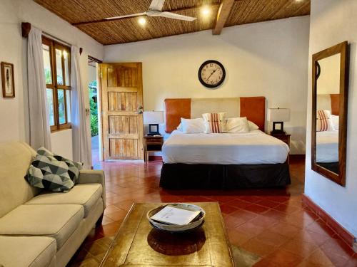 a bedroom with a bed and a couch and a clock at Hotel Tranquilo in Las Peñitas