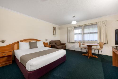 Pegasus Motor Inn and Serviced Apartments في بريزبين: غرفة الفندق بسرير وطاولة