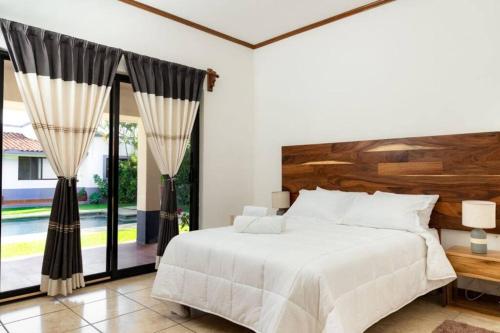 a bedroom with a white bed and a large window at Casa vacacional con piscina para 14 personas in Oaxaca City