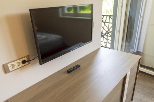 a television on a wall with a remote control on a table at Luxury Villa Četiri Hrasta in Pićan