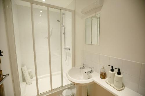 a white bathroom with a shower and a sink at Pigsty Cottage - Rudge Farm Cottages in Bridport