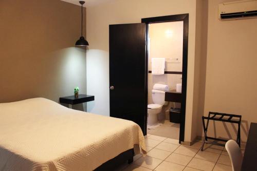 a bedroom with a bed and a bathroom with a toilet at Hotel Magnolia in Tampico