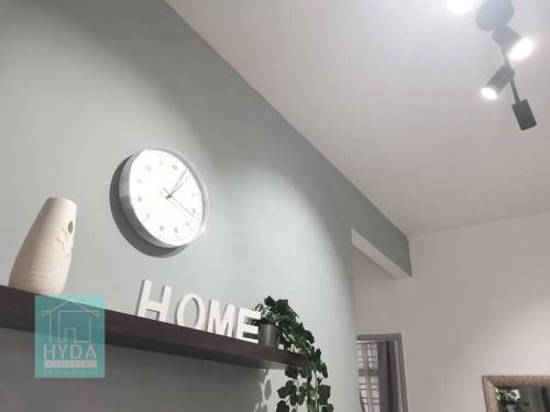 a clock on the side of a wall with a plant at HYDA Homestay Melaka, Durian Tunggal in Kampong Tengah