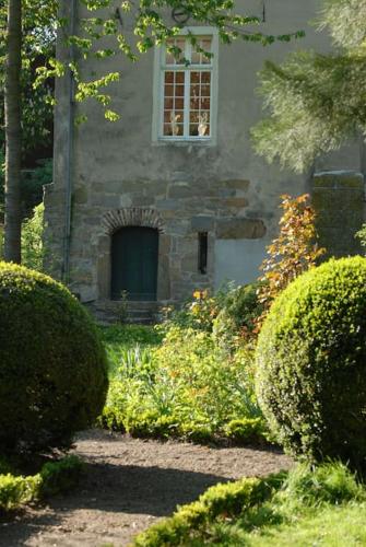 a stone house with a window and two bushes at Haus Keppelborg: ZI Ferdinand mit Rosengartenblick in Heek
