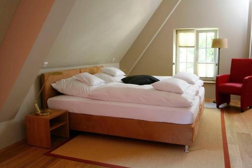 1 dormitorio con 1 cama con sábanas blancas y silla roja en Haus Keppelborg: ZI Ferdinand mit Rosengartenblick, en Heek