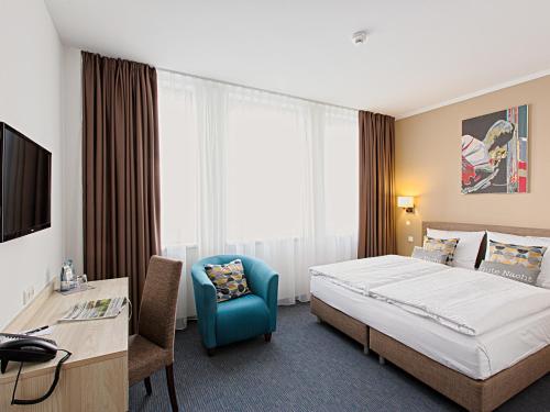 um quarto de hotel com uma cama, uma secretária e uma cadeira em BO Hotel Hamburg em Hamburgo