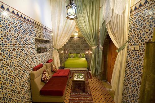 a living room with a green bed and curtains at Riad Dar Jabador in Sale