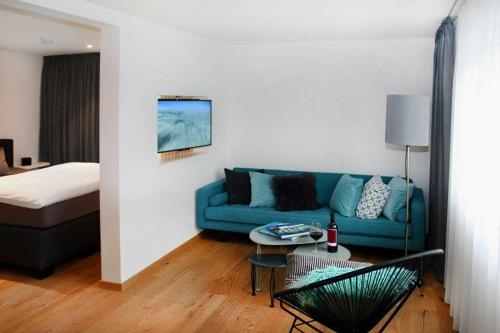 ein Wohnzimmer mit einem blauen Sofa und einem Bett in der Unterkunft Adlerhorst - Boarding House in Michelstadt