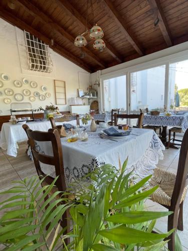 uma sala de jantar com mesa, cadeiras e janelas em Masseria I Raffi b&b em Monopoli