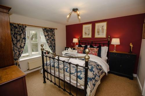 a bedroom with a bed and a red wall at Milkmaids Cottage - Rudge Farm Cottages in Bridport