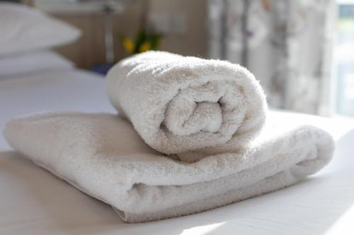 a pile of white towels sitting on a bed at Nature Haven Hot Tub Lodge 30 Cameron, St Andrews in St. Andrews