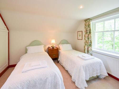 two twin beds in a room with a window at Pinclanty Cottage in Pinmore