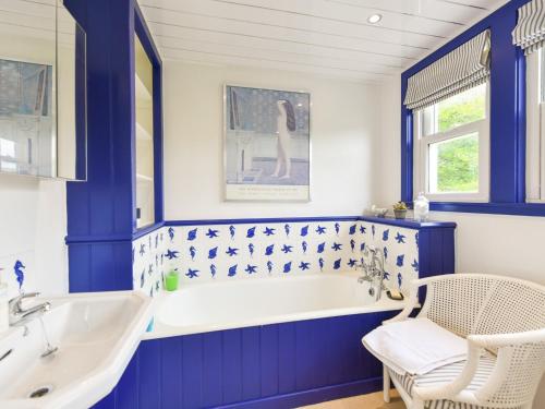 a blue bathroom with a tub and a sink at Pinclanty Cottage in Pinmore