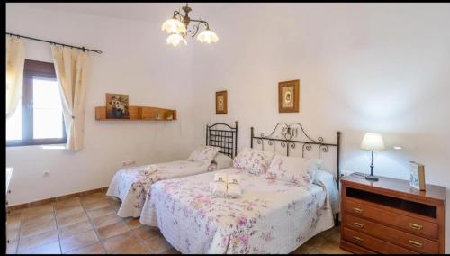 a bedroom with two beds and a dresser and a window at Casa Rural VILLAMADA in El Real de la Jara