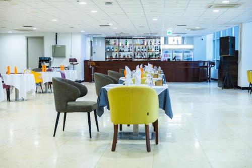 a dining room with tables and chairs and a yellow chair at The View Hotel Restaurant & Sky Lounge in Freetown