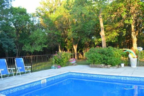 una piscina con 2 sillas azules y árboles en Casa en Villa Animí (Córdoba) en La Granja