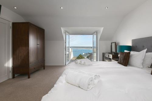 a bedroom with a large white bed with a window at Chy Lowen in Carbis Bay