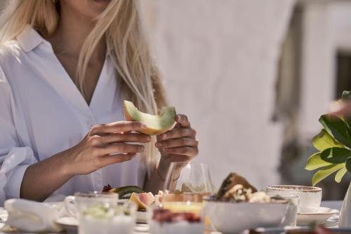 a woman sitting at a table eating a piece of food at Yria Island Boutique Hotel & Spa in Parasporos