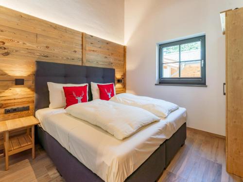 a bedroom with a large bed with red pillows at Pinzgau Lodge 1B in Wald im Pinzgau