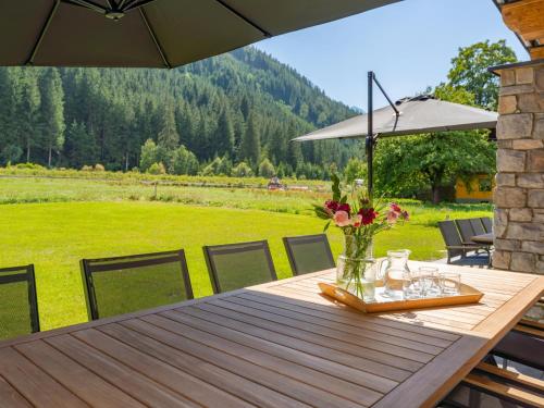 a wooden table with a vase of flowers and an umbrella at Pinzgau Lodge 1B in Wald im Pinzgau