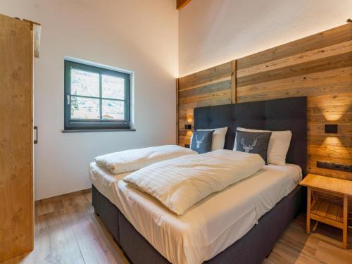 - une chambre avec un grand lit et un mur en bois dans l'établissement Pinzgau Lodge 1A 1B, à Wald im Pinzgau