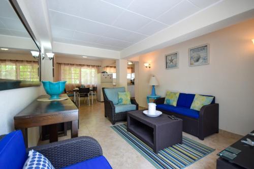 a living room with a blue couch and chairs at 3 min walk from the beach - Blue Waters 25 Apt 3 apts in Bridgetown