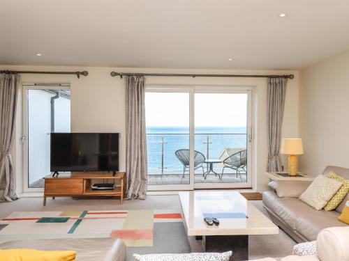 a living room with a television and a large window at Ocean View in Carbis Bay
