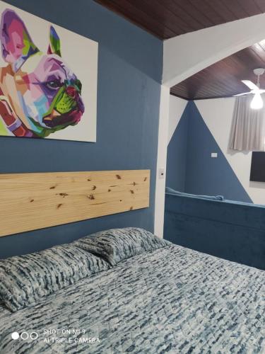 een slaapkamer met een bed met een schilderij van een hond aan de muur bij Suite 237 in Itanhaém