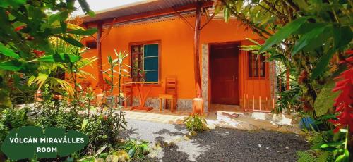 an orange house with an orange door and a porch at Jardin entre Montañas in Bijagua