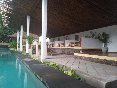 a swimming pool next to a building with a house at Ocean Prana Village in Amed