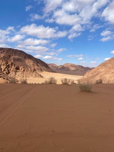 a desert with mountains in the background and a dirt field at Syndebad desert camp in Wadi Rum