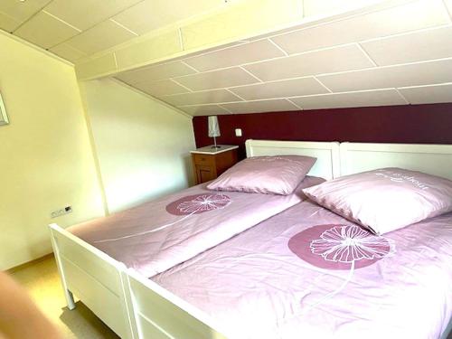a bed with two pink pillows on it in a room at Jünkerath Romantic Garden Stay in Jünkerath