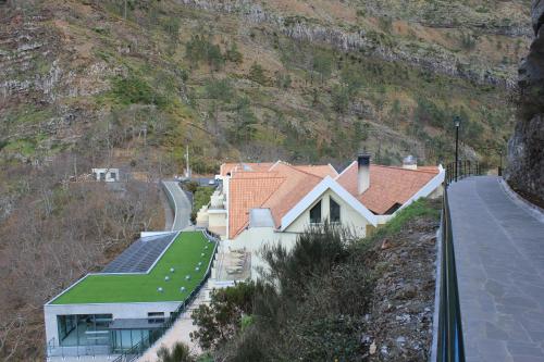 a house with a roof with a green yard at Eira do Serrado - Hotel & Spa in Curral das Freiras