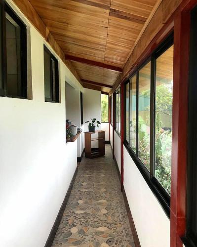a hallway of a house with a table and windows at Alisson Hotel y Restaurant in Monteverde Costa Rica