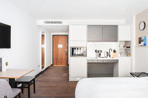 a kitchen with white cabinets and a dining room with a table at Staybridge Suites Brighton by IHG in Brighton & Hove
